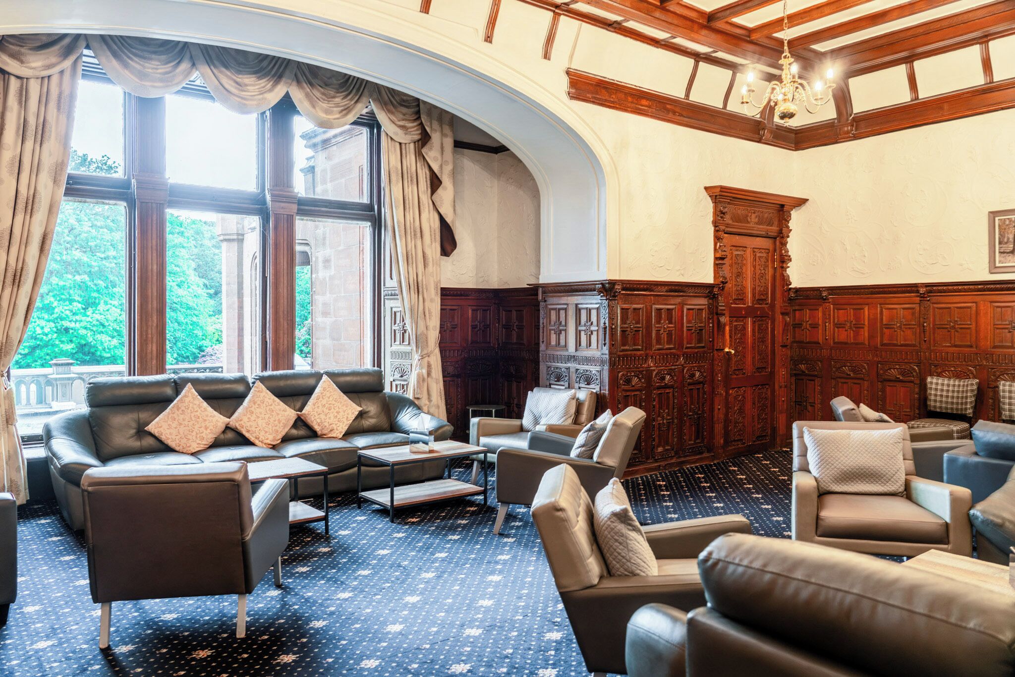Een hotel lobby met leren banken, een kamer met een patroon en een groot houten kast.