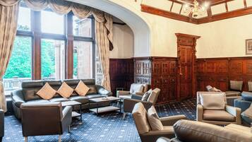Een hotel lobby met leren banken, een kamer met een patroon en een groot houten kast.
