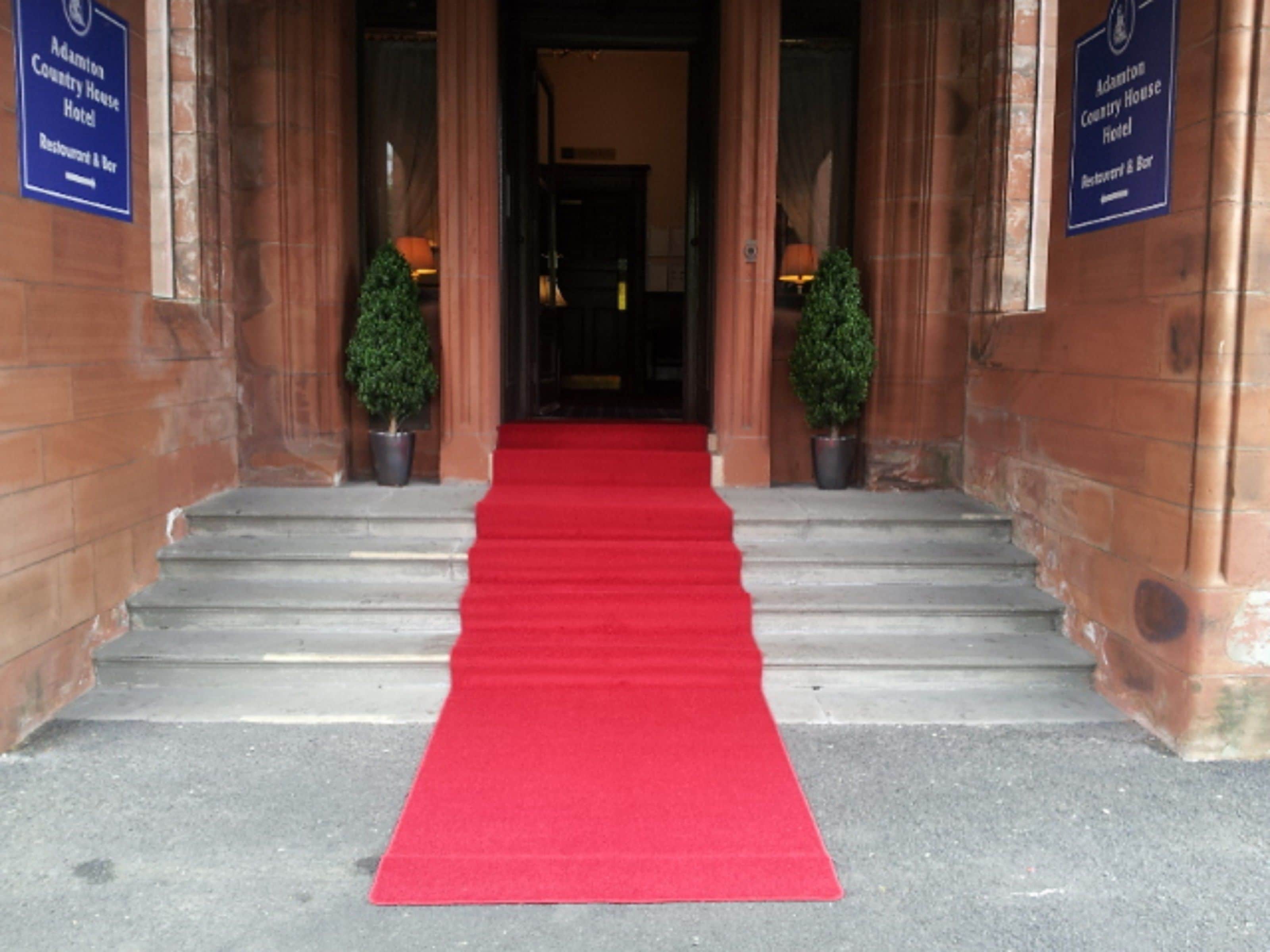 Una alfombra roja que conduce a un edificio con dos letreros que dicen "Adamton Country House Hotel Restaurant & Bar".