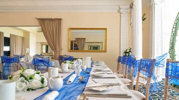 A long banquet table set with white tablecloths, blue chair covers, and white floral centerpieces.