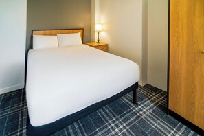 A hotel room with a large bed, a nightstand with a lamp, and a wooden wardrobe. - Adamton Country House Hotel (Prestwick)