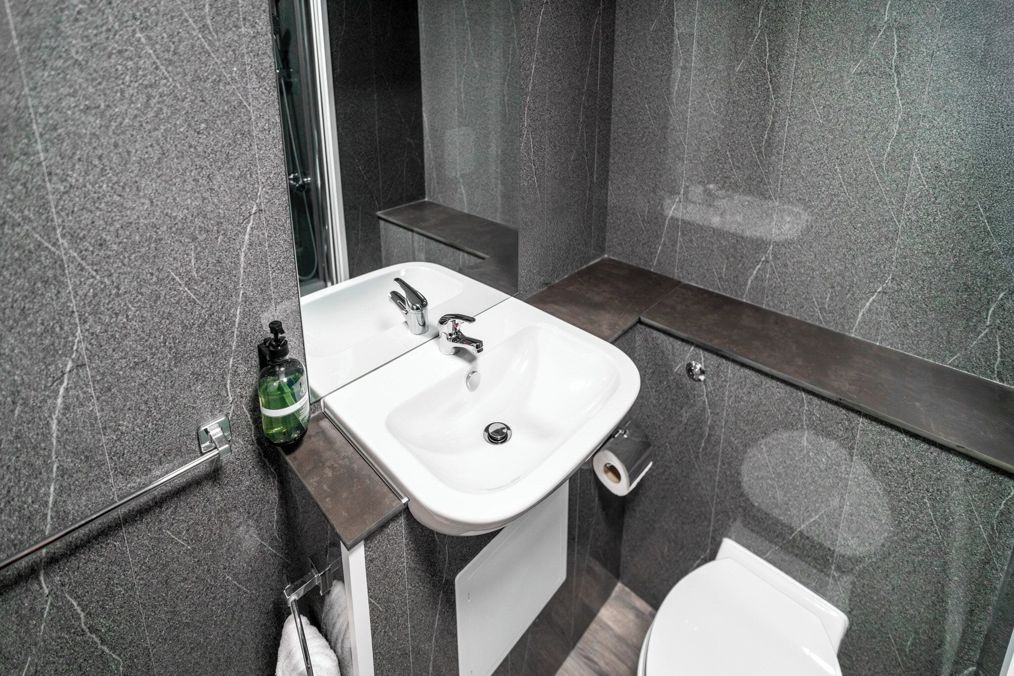 Un baño con lavamanos blanco, un espejo y un inodoro.