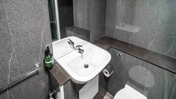 Un baño con lavamanos blanco, un espejo y un inodoro.