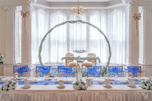A formal dining room with a long table, blue chairs, and a decorative arch. - Adamton Country House Hotel (Prestwick)