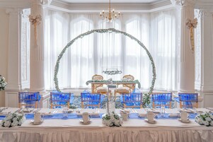 Un comedor formal con una larga mesa, sillas azules y un arco decorativo.