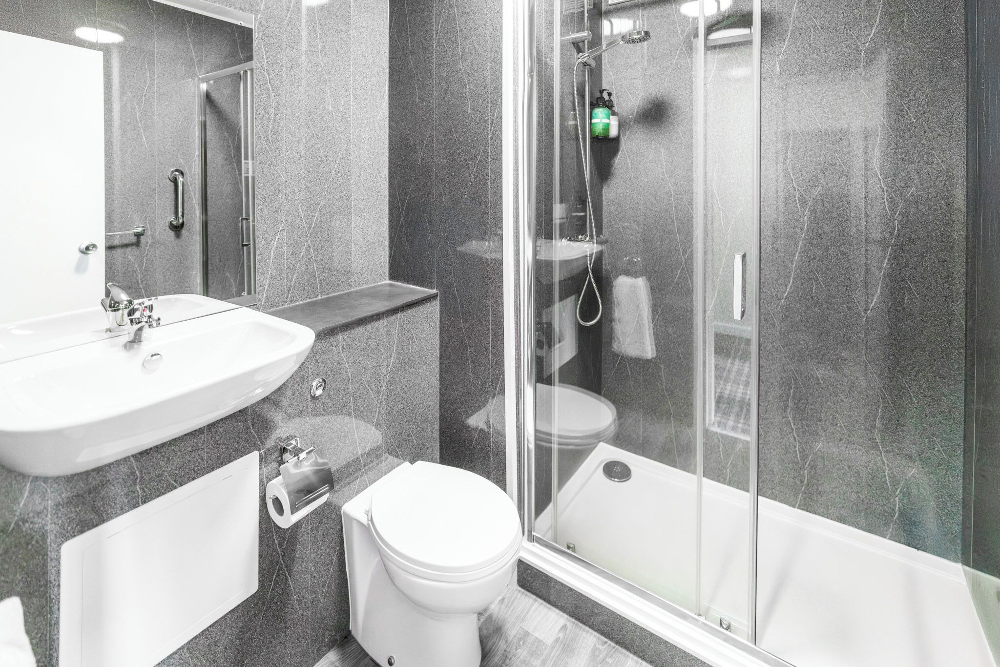 A modern bathroom with a glass-enclosed shower, a white sink, and a toilet.