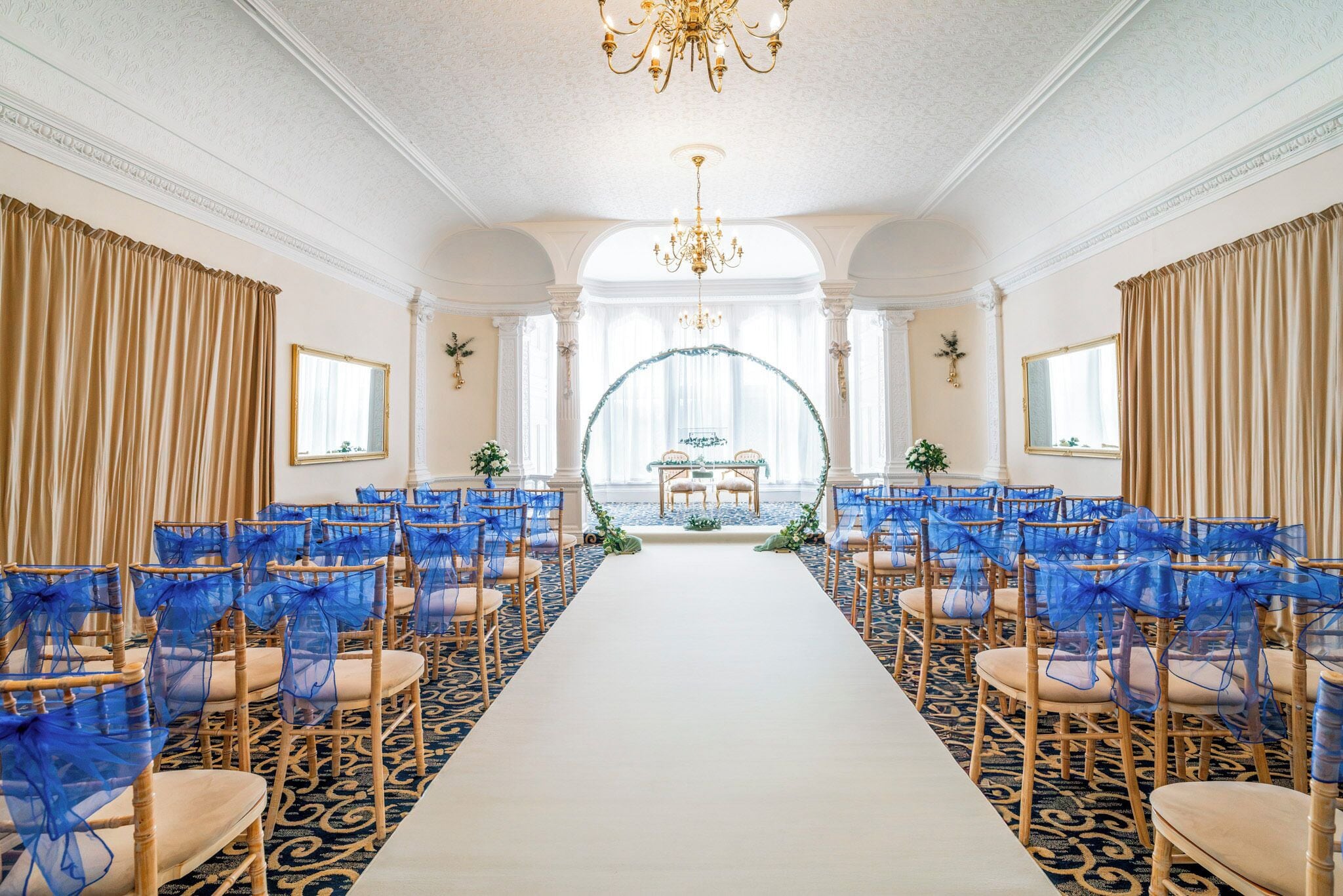 A formal event space with rows of chairs, a central aisle, and a decorative archway.