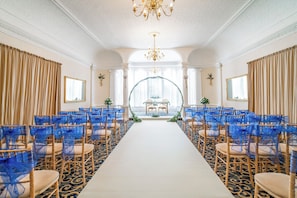 A formal event space with rows of chairs, a central aisle, and a decorative archway.