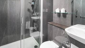 Ein modernes Badezimmer mit Duschkabine aus Glas, einem weißen Waschbecken und einer Toilette.