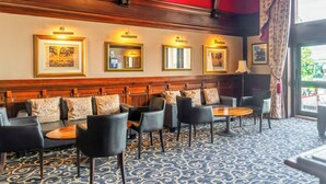 A hotel lobby with a seating area, framed artwork on the walls, and a patterned carpet. - Adamton Country House Hotel (Prestwick)