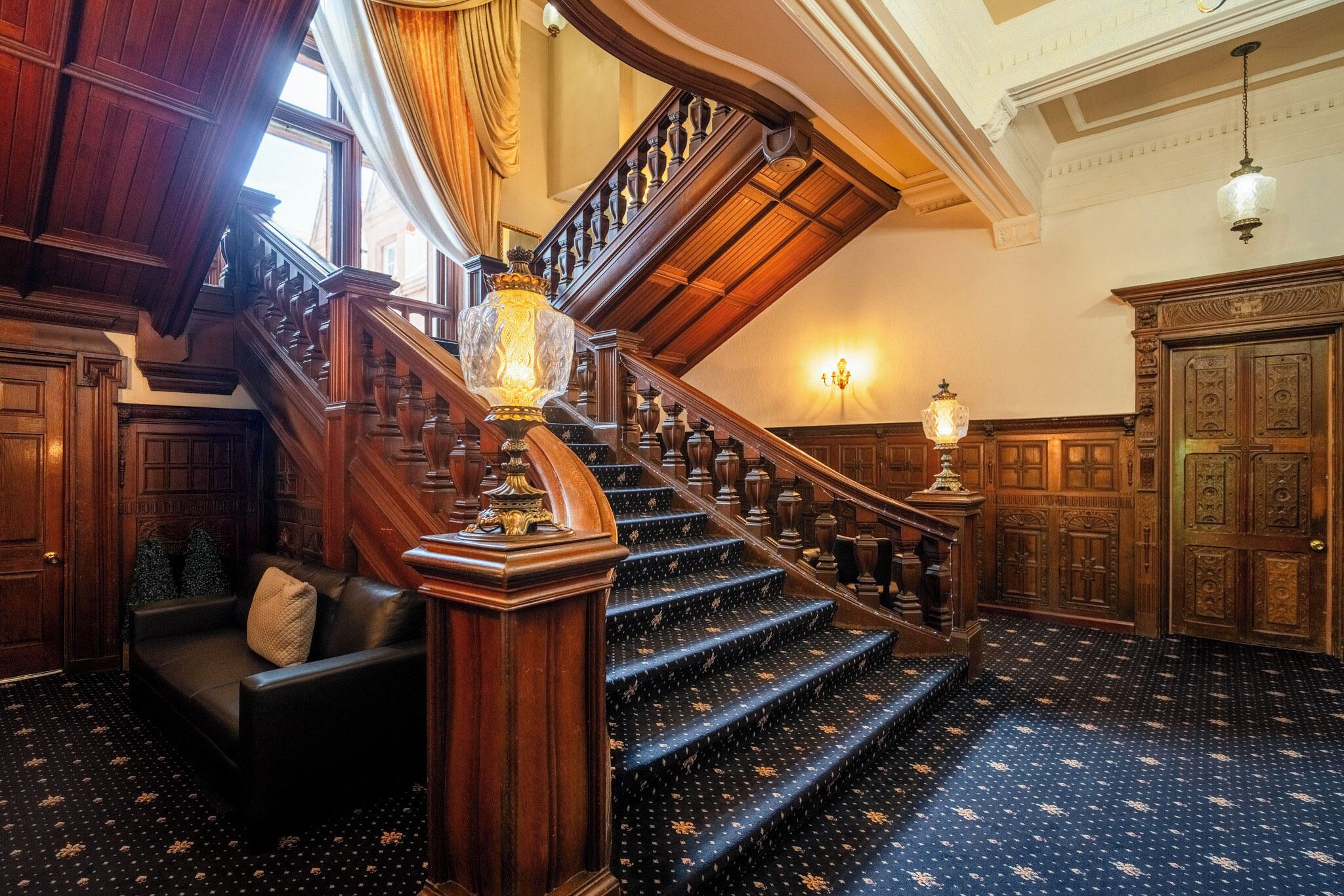 A grand staircase with ornate woodwork and a patterned carpet.