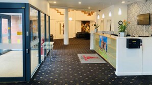 A hotel reception area with a reception desk, seating area, and a staircase leading to another floor. - Adamton Country House Hotel (Prestwick)