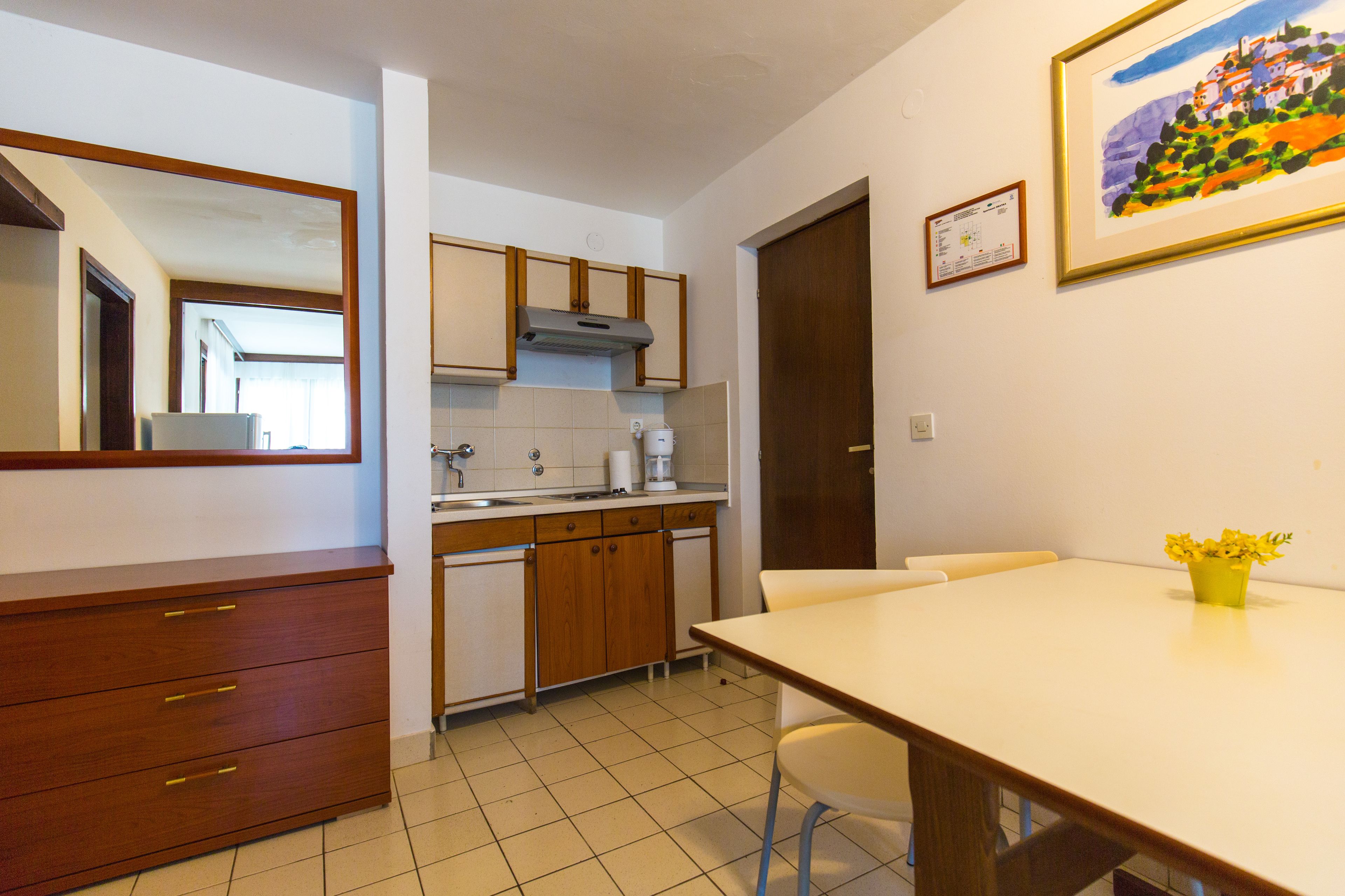 A kitchen with wooden cabinets, a white countertop, and a dining table with chairs.