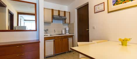 A kitchen with wooden cabinets, a white countertop, and a dining table with chairs.