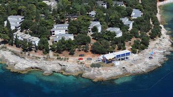 Vista aérea de una zona residencial costera con casas, un litoral rocoso y aguas azul cristalino.