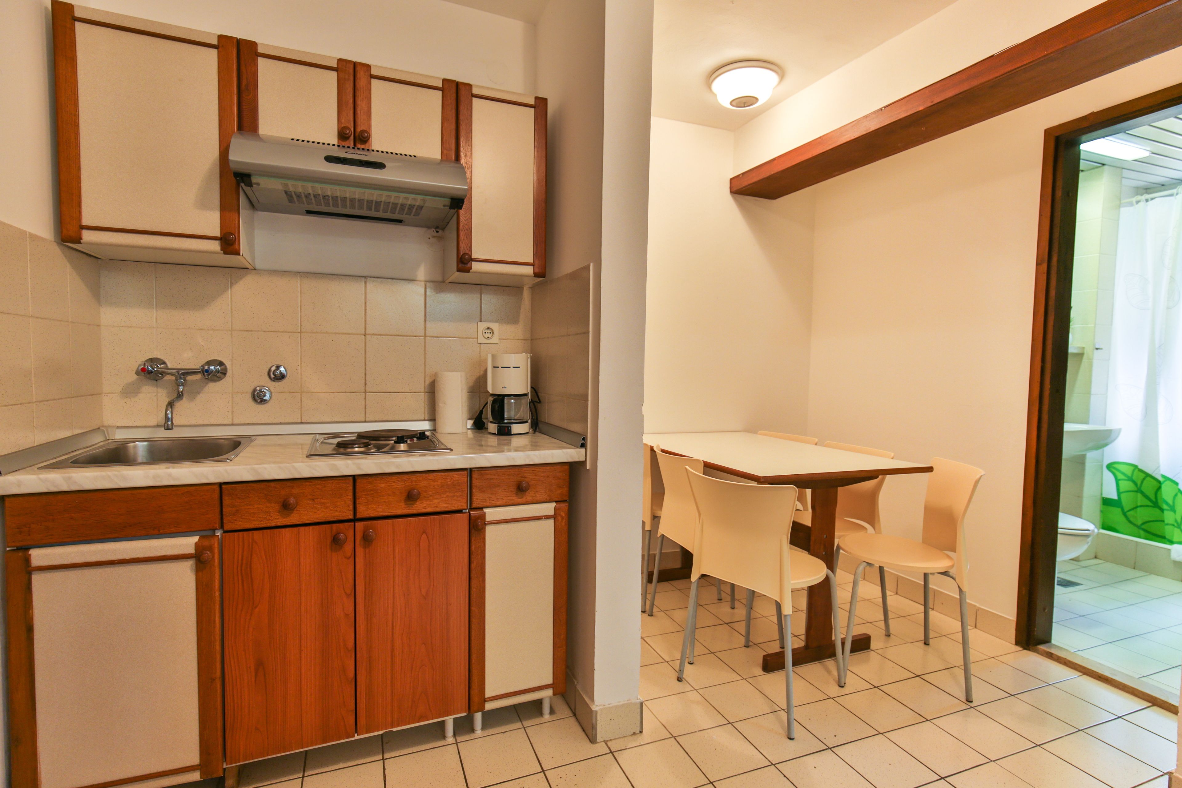 A compact kitchen with wooden cabinets, a built-in stove, and a coffee maker.