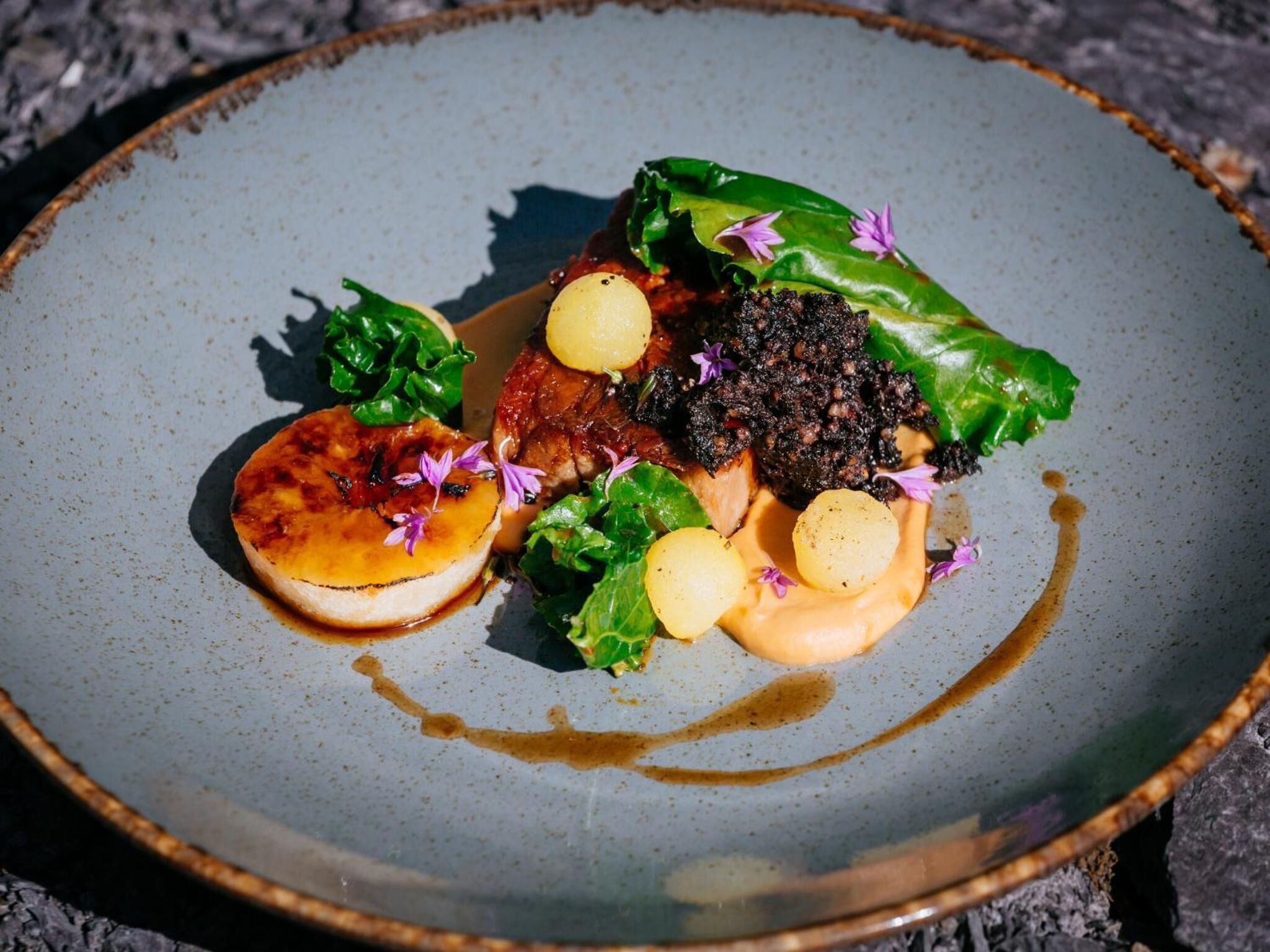 A plate with a variety of food items including a piece of meat, potatoes, and greens.