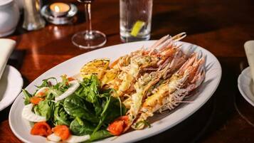 A plate of grilled shrimp with a side salad on a wooden table.
