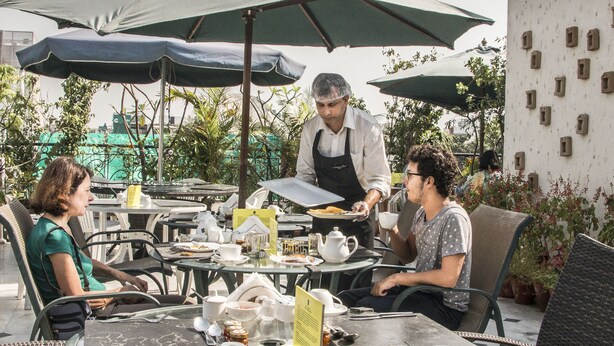 Café al aire libre con mesas, sillas y sombrillas.