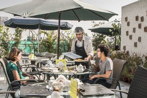 Un café en plein air avec des tables, des chaises et des parasols.