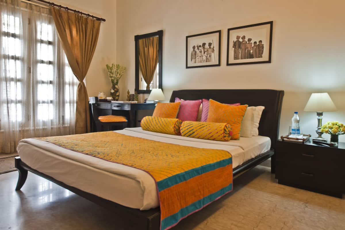 A neatly made bed with a colorful bedspread, a bedside table with a lamp, and two framed pictures on the wall.