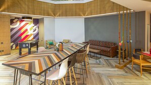 A spacious room with a long table, chairs, a sofa, and a pool table. There is a staircase leading to an upper level. - Ginger Pune Wakad (Paud)
