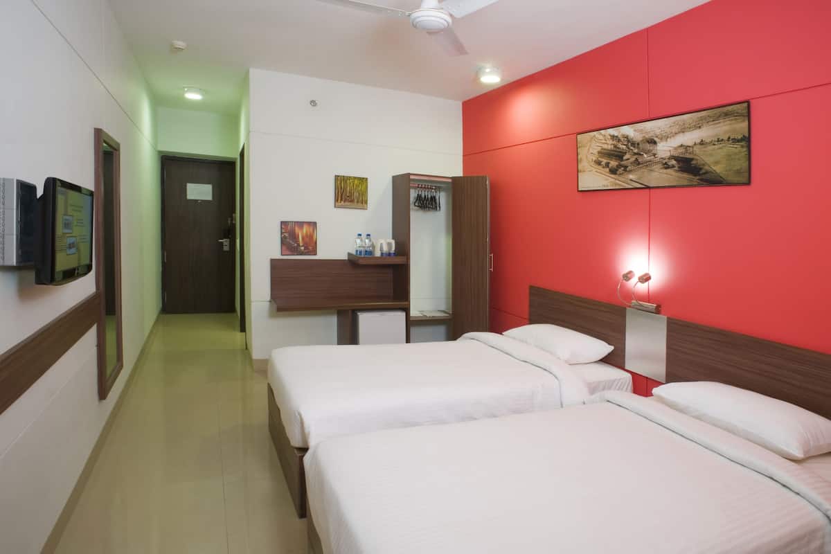 Habitación de hotel con dos camas, un escritorio con silla, armario, televisión y un cuadro en la pared.