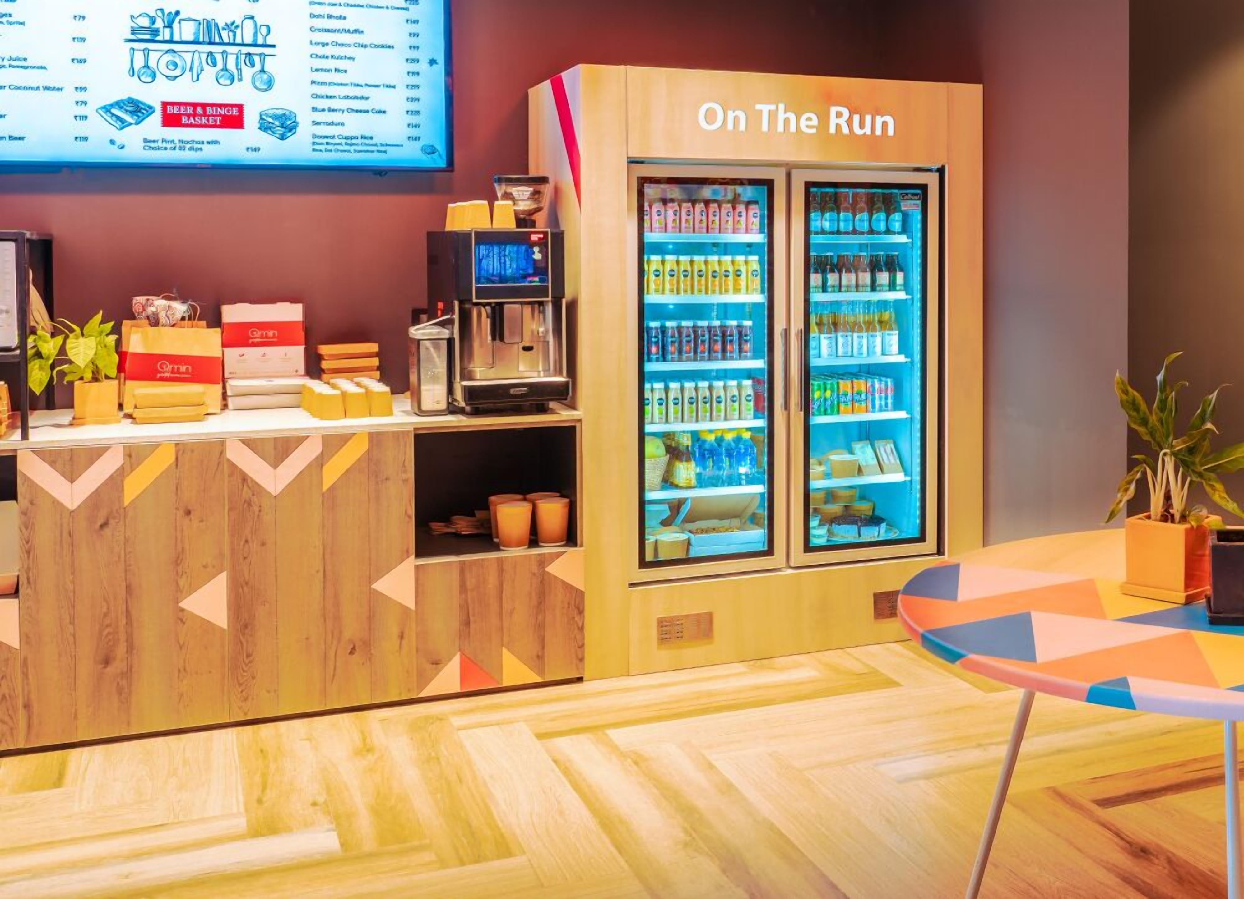 Una barra con una máquina de café, un refrigerador de bebidas con el rótulo "On The Run" y un tablero de menú.