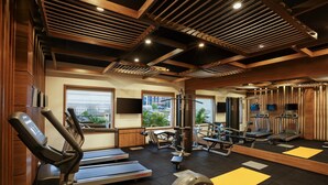 A gym with treadmills, weight machines, and a mirror. - Ginger Pune Wakad (Paud)