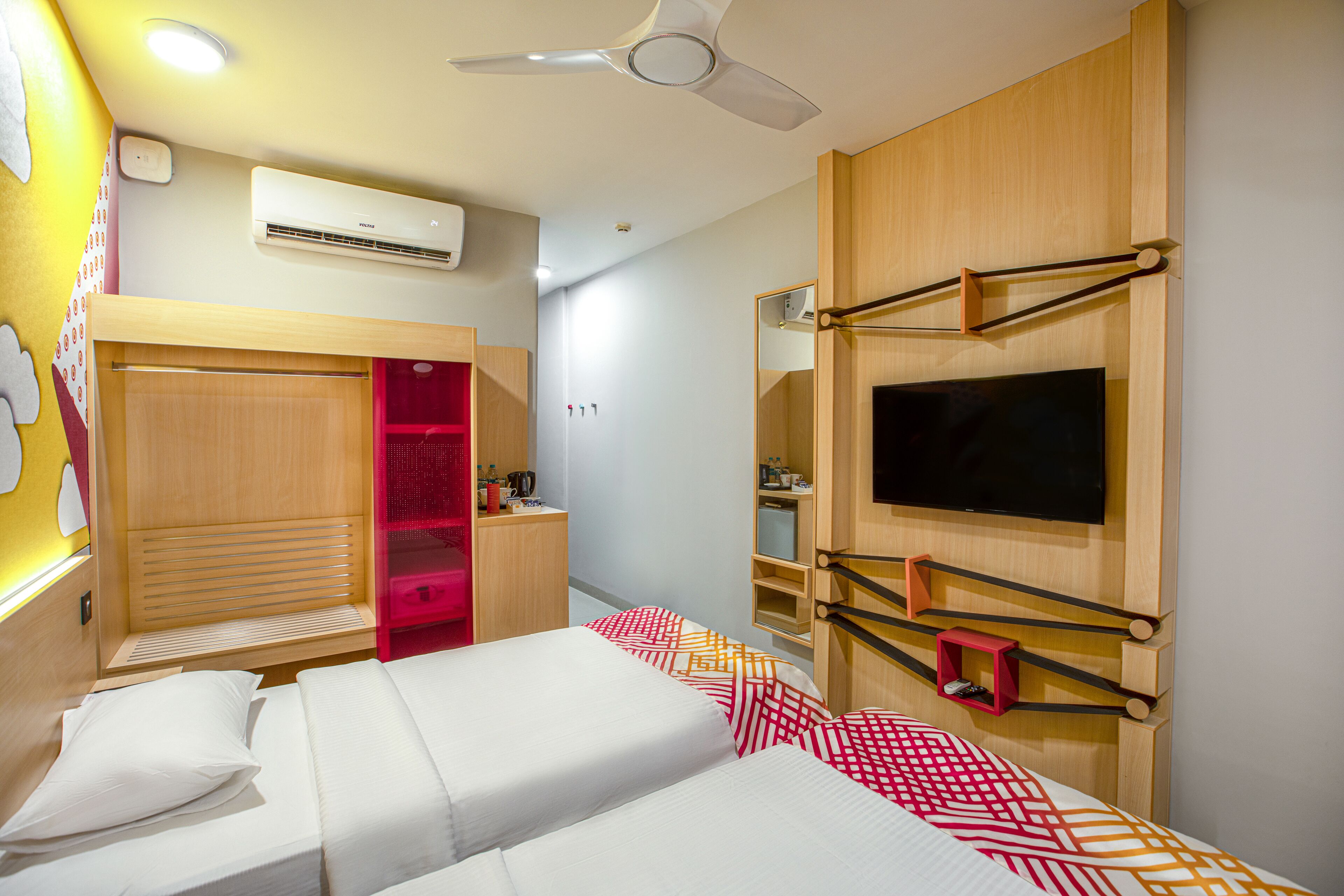 A hotel room with a bed, a wardrobe, a TV, and an air conditioning unit.