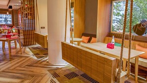 A modern interior with a wooden dining area, a seating area with a view, and a staircase with a railing. - Ginger Pune Wakad (Paud)
