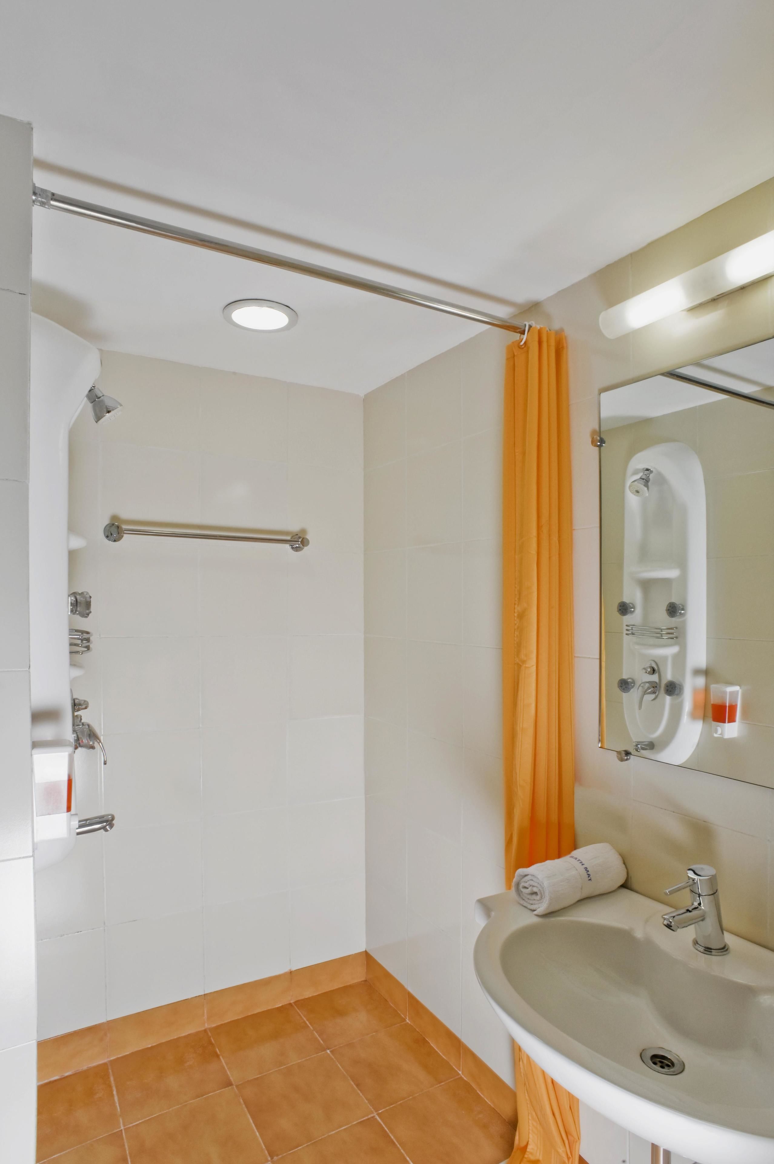 A bathroom with a shower, a sink, a mirror, and a towel rack.