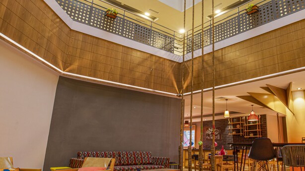 A multi-level atrium with a central staircase, seating areas, and a dining space. - Ginger Pune Wakad (Paud)