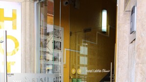 A hotel entrance with a glass door, a staircase, and a sign for Hotel Leiria Classic. - Hotel Leiria Classic (Leiria)