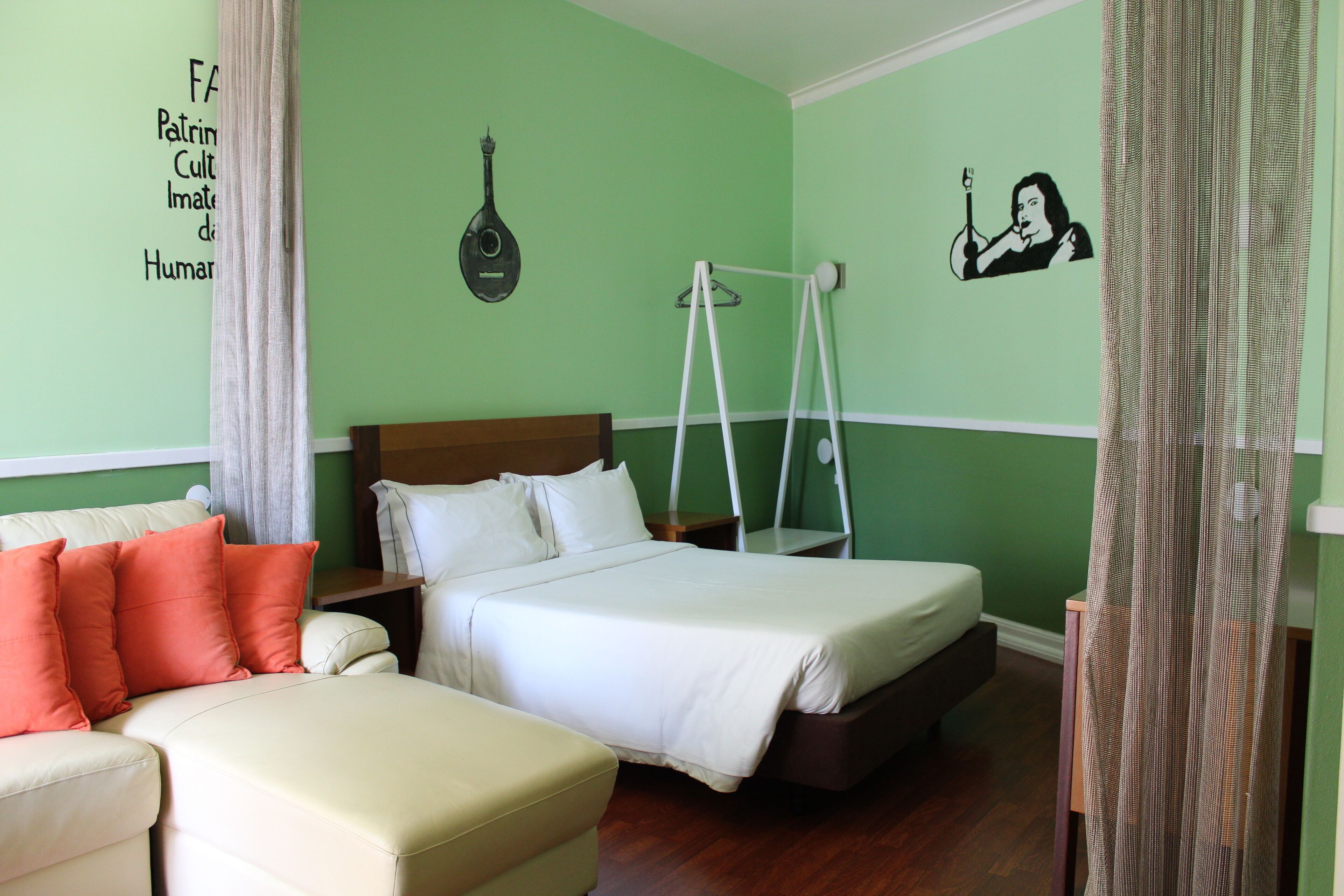 Una habitación con una cama, un sofá pequeño y una silla colgante.