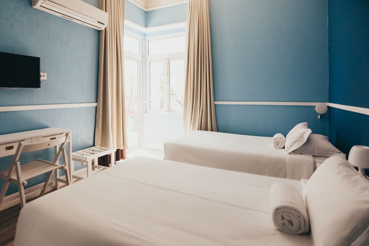 Ein Hotelzimmer mit zwei Betten, einem Schreibtisch und einem Fernseher.