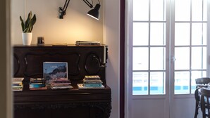 A room with a wooden desk, a potted plant, a lamp, and a window with a view. - Hotel Leiria Classic (Leiria)