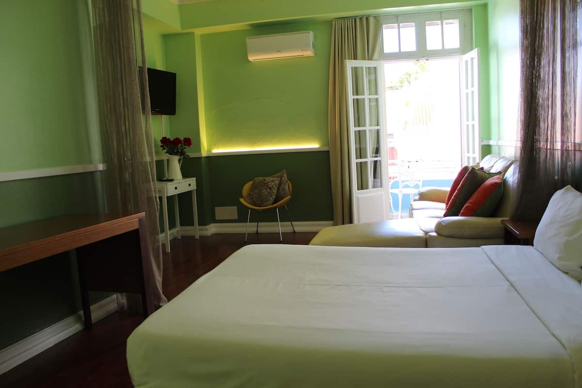 Ein Hotelzimmer mit einem großen Bett, einem Schreibtisch, einem Sessel und Blick ins Freie.