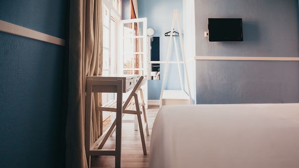 A bedroom with a bed, a desk, a ladder, and a TV mounted on the wall. - Hotel Leiria Classic (Leiria)
