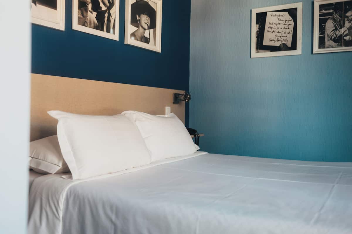 Ein ordentlich bezogenes Bett mit weißen Leinentüchern in einem Zimmer mit blauen Wänden.