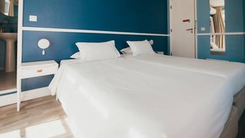 Una habitación de hotel con una cama grande, una mesita de noche, un espejo y una puerta.