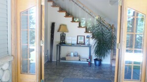 A wooden staircase leading to a second floor, a desk with a lamp and framed certificates, a potted plant, and a stone wall. - Maple View Bed and Breakfast (Nanaimo)