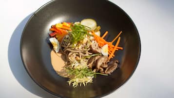 A bowl of noodles with vegetables and a boiled egg.