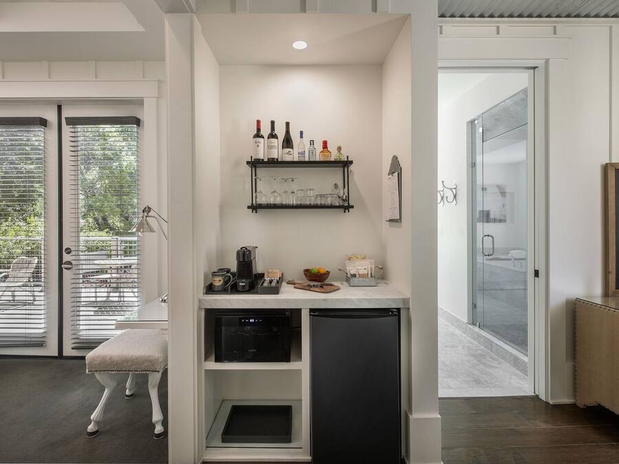 A compact kitchen with a built-in dishwasher, a coffee machine, and a small countertop with various items.