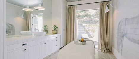 Een moderne badkamer met een grote spiegel, witte kastjes, een wastafelmeubel en een bad.