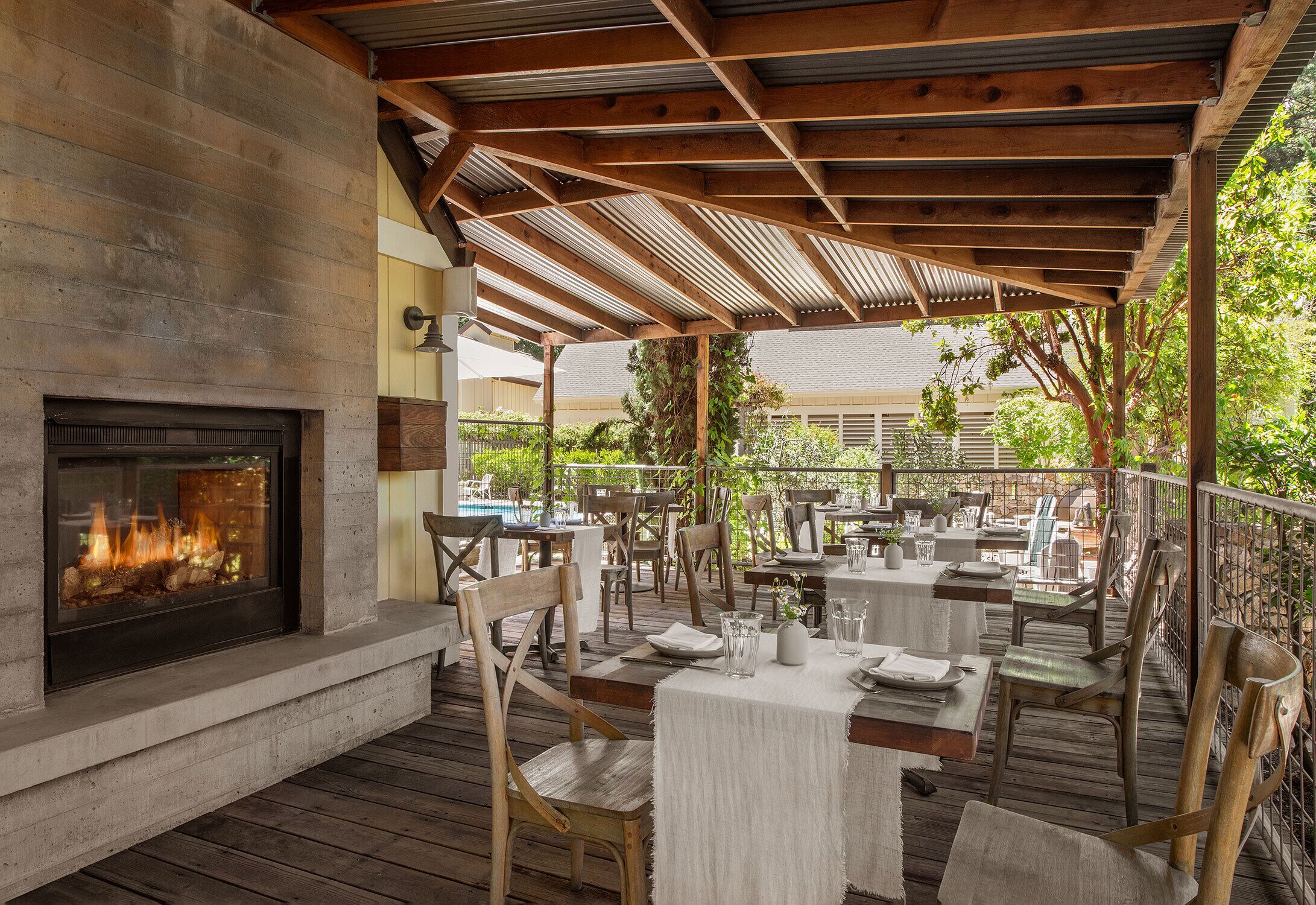 An outdoor patio with tables and chairs, a fireplace, and a view of the surrounding area.