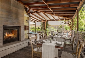 Un patio al aire libre con mesas y sillas, una chimenea y vistas del entorno.