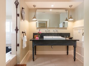 A bathroom with a dark wooden vanity, a large mirror, two pendant lights, and a white sink.