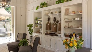 A well-organized living room with a large white shelving unit filled with various items, a comfortable seating area with a sofa and armchairs, and a potted plant adding greenery. - Farmhouse Inn (Forestville)