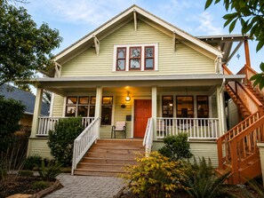 A two-story house with a front porch, wooden stairs, and a visible staircase on the right. - Bluebird Guesthouse (Portland)